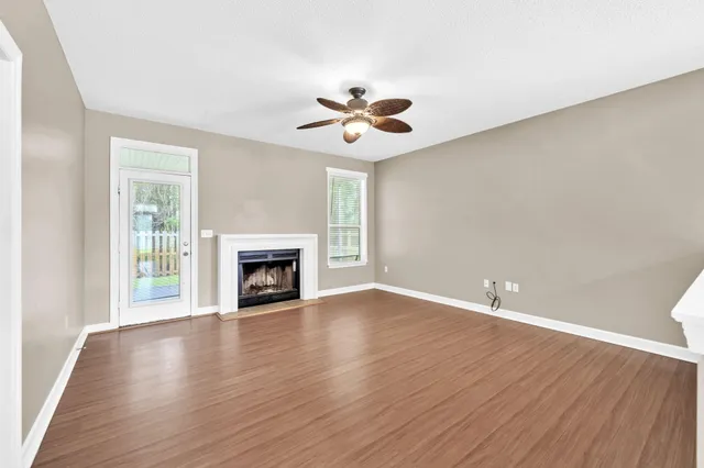 a view of an empty room with wooden floor fireplace and a window