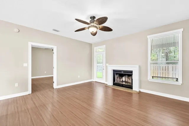 a view of an empty room with wooden floor and a window