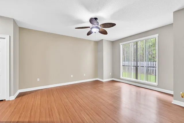 an empty room with wooden floor and windows