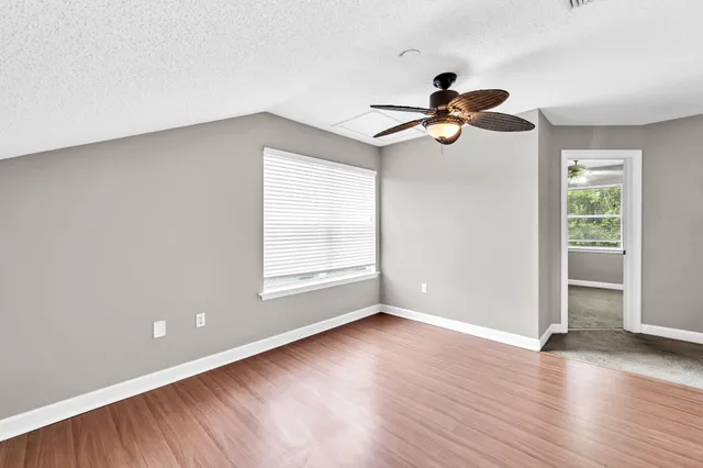 an empty room with windows and chandelier fan