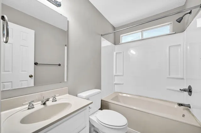 an empty room with windows and chandelier fan