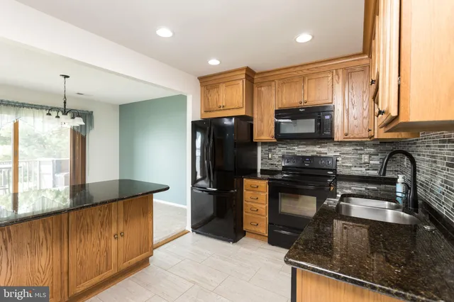 a kitchen with stainless steel appliances granite countertop a refrigerator a stove a sink and a microwave