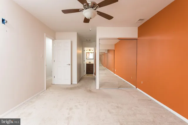 an empty room with closet and a ceiling fan