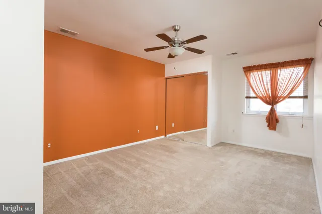 an empty room with windows and fan