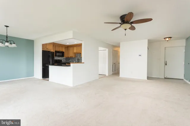 a view of a livingroom with a ceiling fan a kitchen view and a refrigerator