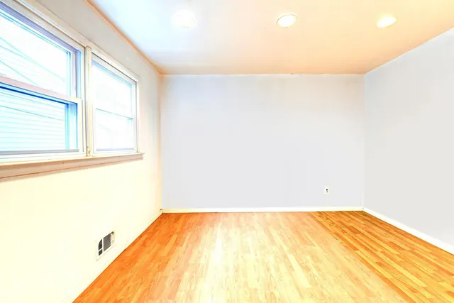 a view of a big room with wooden floor and a window