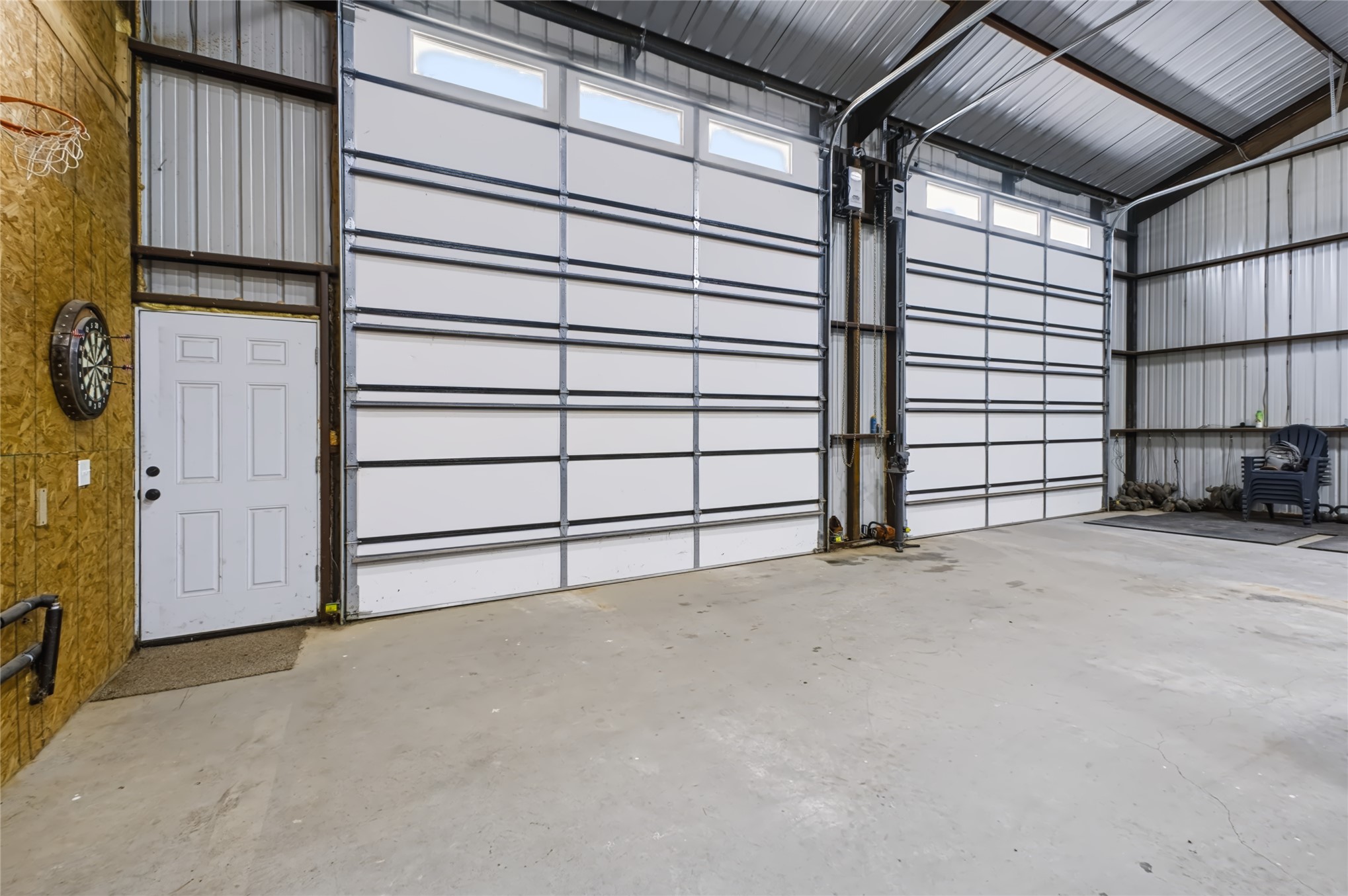 3607 South Half Bank Road Atoka, OK 74525 - Photo 37 of 82 Spacious concrete floor with two large roll-up doors featuring upper transom windows and a paneled entry door