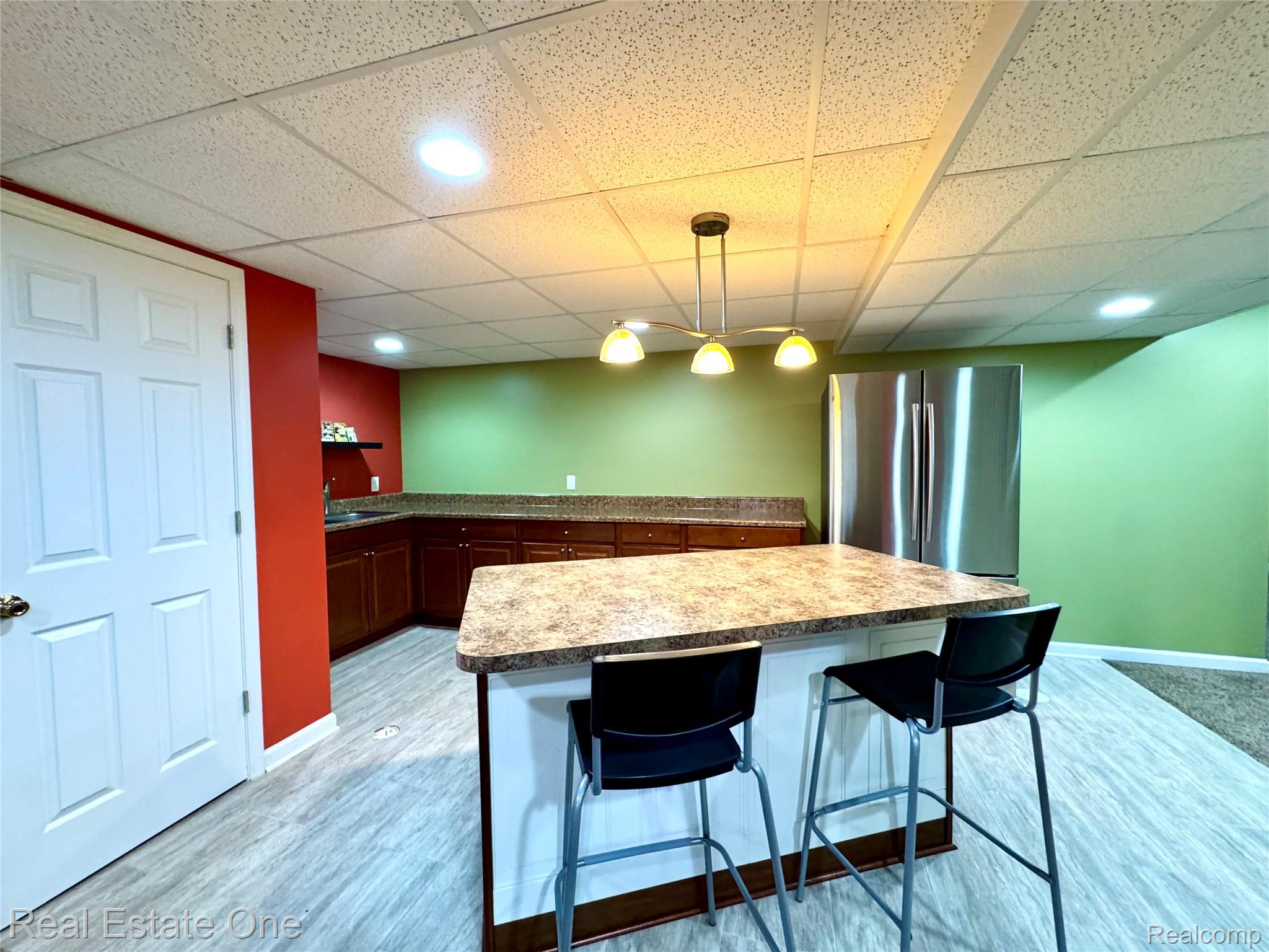 1215 Letica Drive Rochester, MI 48307 - Photo 26 of 43 Kitchen with a breakfast bar area, decorative light fixtures, freestanding refrigerator, light wood finished floors, and a kitchen island