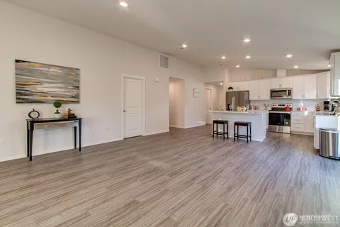 a kitchen with stainless steel appliances wooden floor and chairs