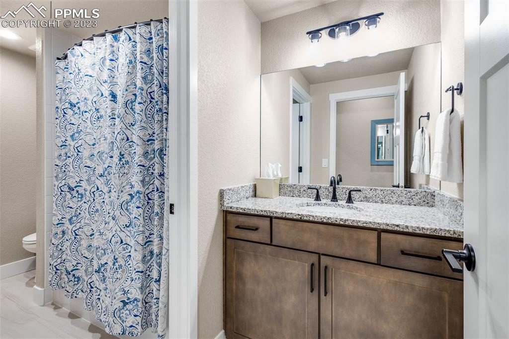 2960 Longhorn Rdg View Peyton, CO 80831 - Photo 34 of 49 a bathroom with a granite countertop sink a mirror and shower