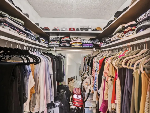 a view of walk in closet with clothes and shoes