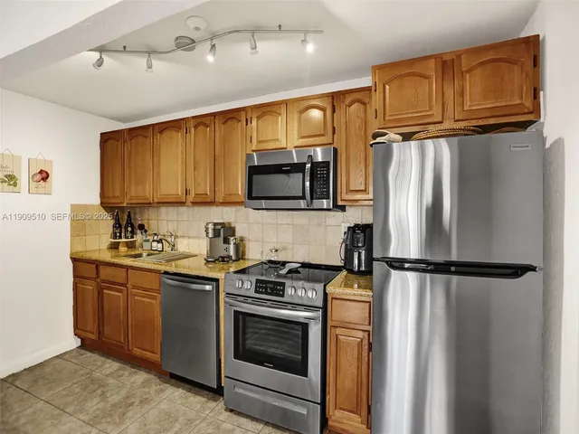 a kitchen with stainless steel appliances granite countertop a refrigerator sink and stove