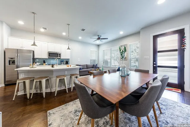 a view of a dining room and livingroom with furniture wooden floor a rug a rug and a kitchen