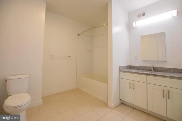 a bathroom with a granite countertop sink a toilet and a bathtub