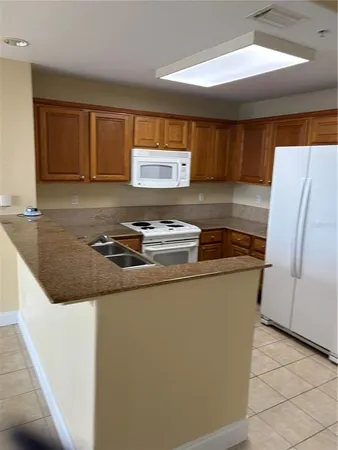 a kitchen with granite countertop a refrigerator and a stove top oven