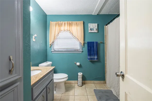 a bathroom with a granite countertop toilet a sink and a mirror