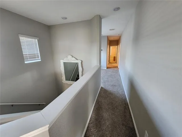 a view of a hallway with wooden floor and a bathroom