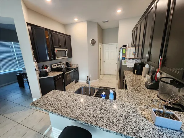 a kitchen with stainless steel appliances kitchen island granite countertop a sink stove and refrigerator