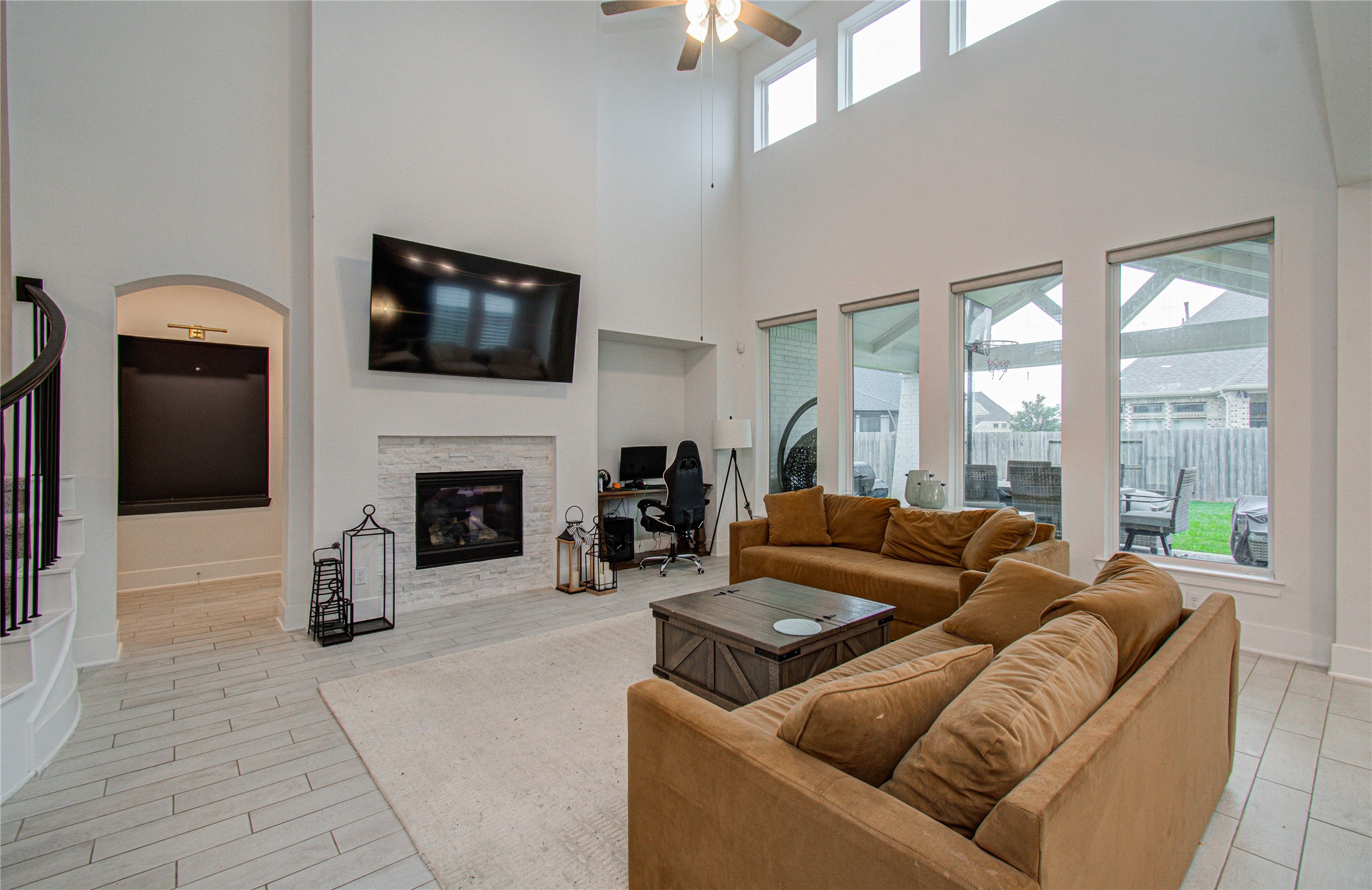 4211 Limestone Terrace Manvel, TX 77578 - Photo 12 of 33 This spacious living room features high ceilings, large windows for natural light, and a modern fireplace. It includes a cozy seating area with a TV mounted above the fireplace, a small office nook, and easy access to the backyard, creating an inviting and functional space.