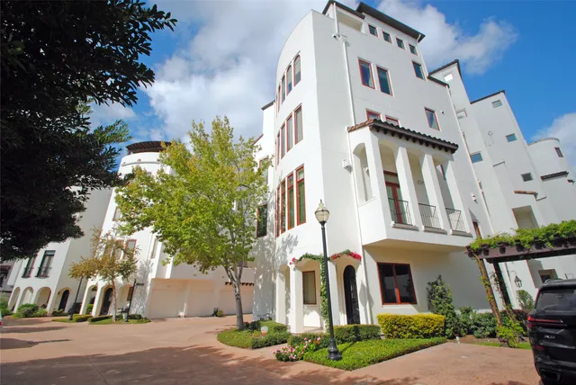 a front view of a multi story residential apartment building with yard and parking