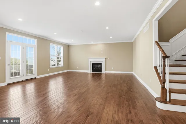 a view of an empty room with wooden floor and a fireplace