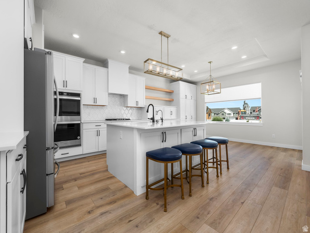 2786 West Hancock Street, Unit 198 Mapleton, UT 84664 - Photo 6 of 33 Gourmet kitchen featuring a large central island with seating, white shaker cabinetry, stainless steel appliances, and wood-finish flooring