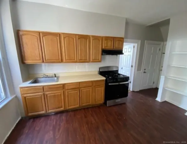a kitchen with granite countertop wooden floors stainless steel appliances and sink