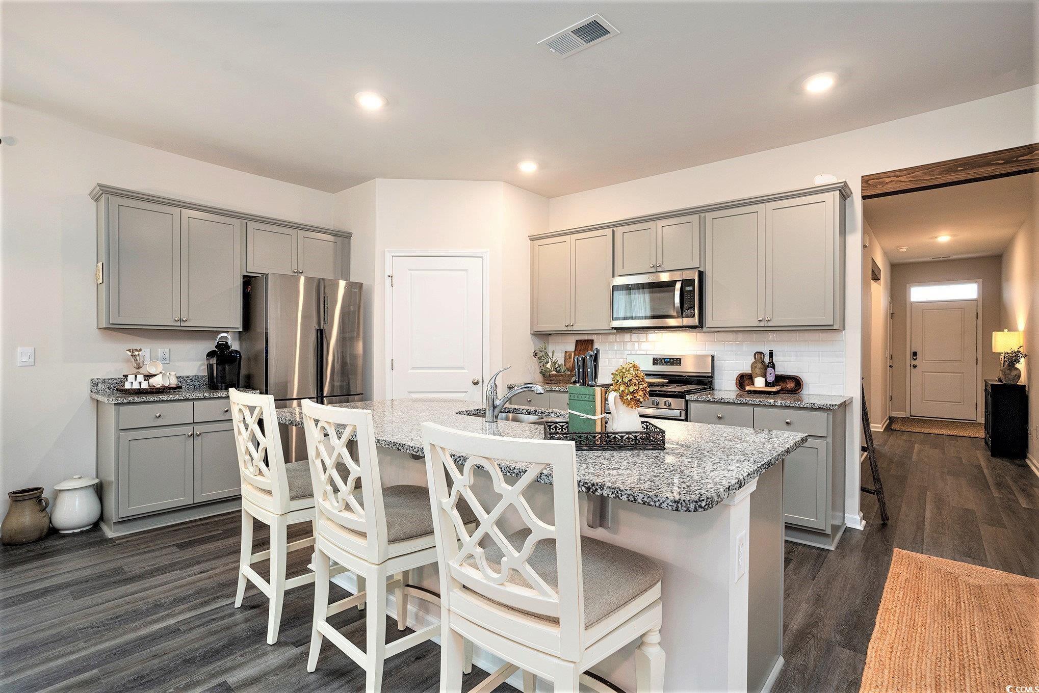 132 Columbus Street Conway, SC 29526 - Photo 14 of 39 Kitchen with gray cabinetry, a kitchen bar, appliances with stainless steel finishes, dark wood-style flooring, and recessed lighting