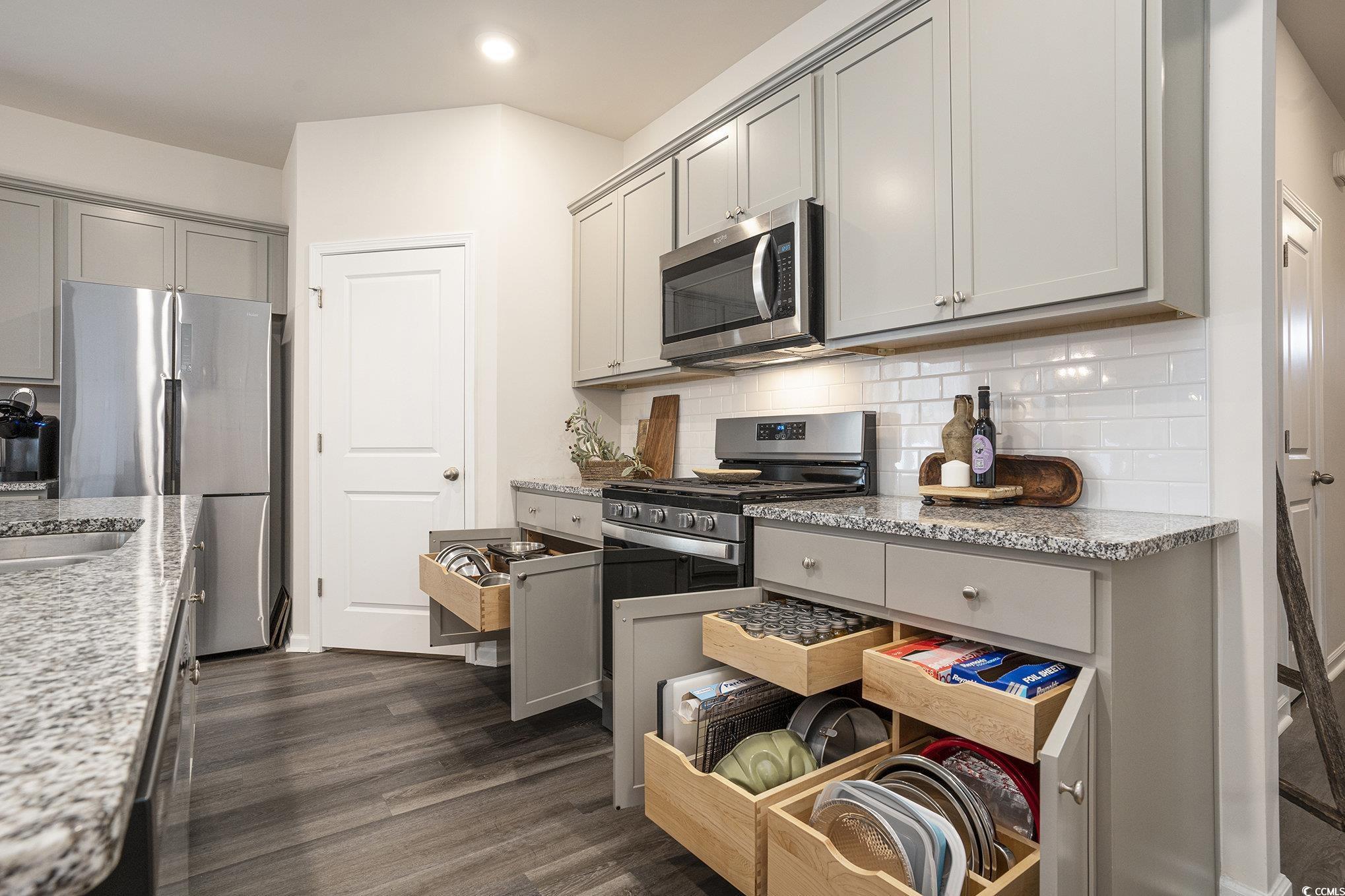 132 Columbus Street Conway, SC 29526 - Photo 15 of 39 Kitchen featuring gray cabinets, appliances with stainless steel finishes, light stone countertops, backsplash, and dark wood finished floors