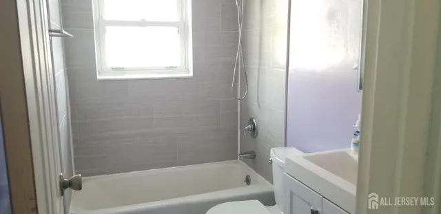 a bathroom with a bathtub toilet and window