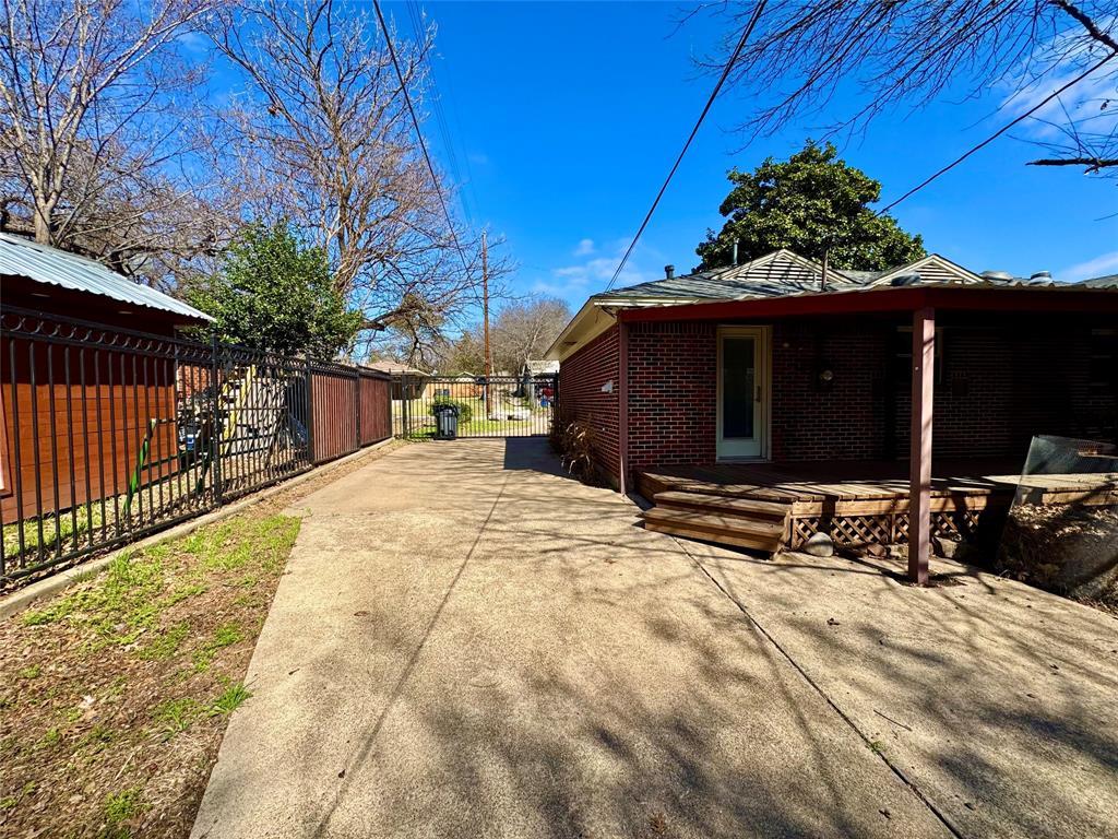 6712 Timothy Drive Dallas, TX 75227 - Photo 16 of 20 View of property exterior with a wooden deck, brick siding, and driveway