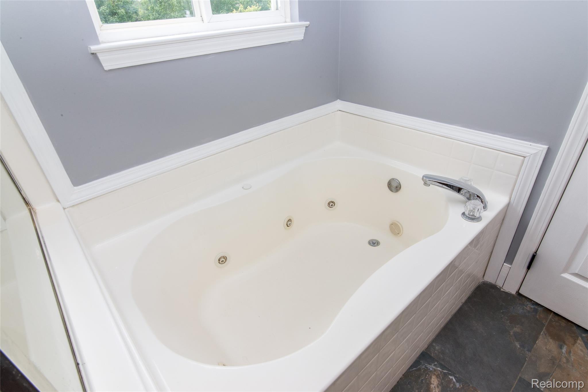 486 Sweet Briar Ridge Linden, MI 48451 - Photo 46 of 69 Recessed jetted tub with integrated chrome fixtures, tile surround, and slate-finish floor