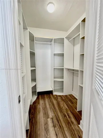 a room with walk in closet and wooden floor