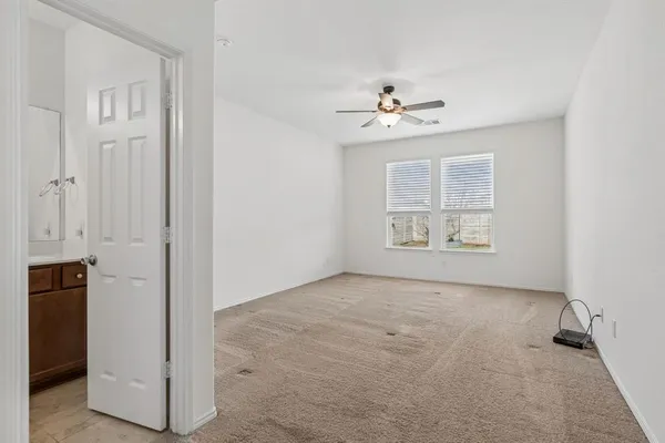 an empty room with windows and ceiling fan