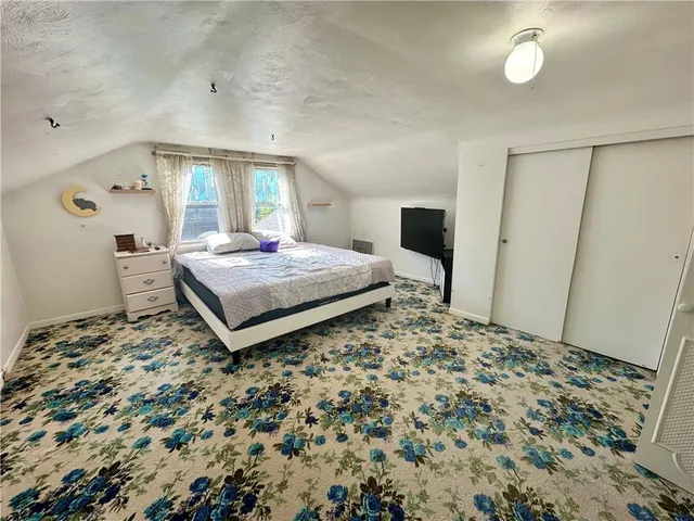 a bedroom with a bed and a flat tv screen on dresser