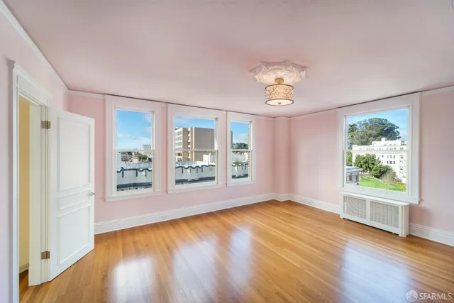 a view of an empty room with a window and wooden floor