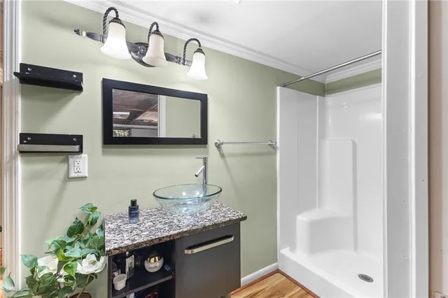 a bathroom with a granite countertop sink a mirror and shower
