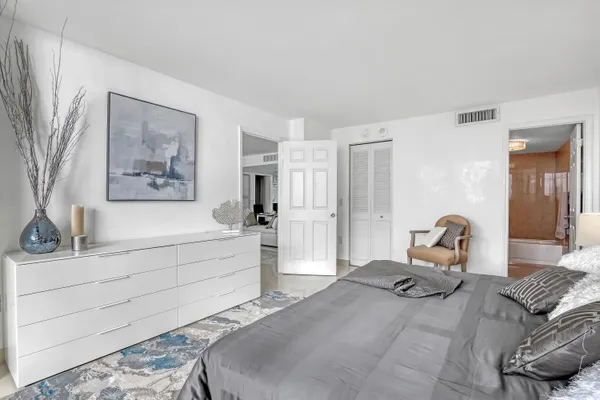 a bedroom with a bed wooden floor and view of living room