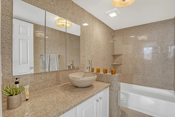 a bathroom with a granite countertop sink a toilet and bathtub