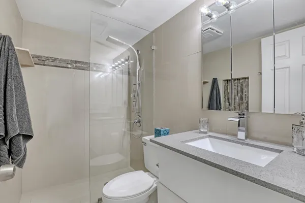 a bathroom with a granite countertop sink toilet and shower