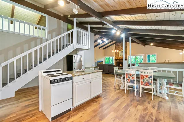 a view of an empty room with wooden floor furniture and a kitchen