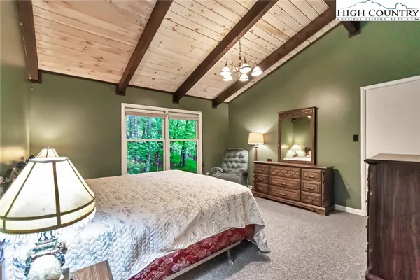 a spacious bedroom with a bed a dresser next to a window