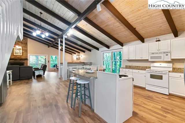a kitchen with stainless steel appliances granite countertop a stove oven and a dining table with wooden floor