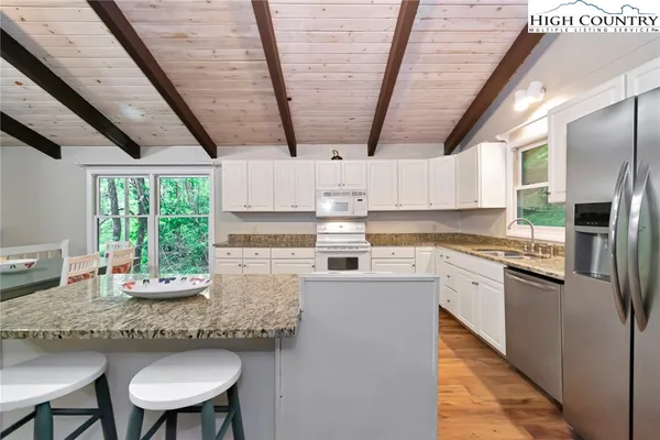 a kitchen with stainless steel appliances granite countertop a stove a refrigerator a sink dishwasher a dining table and chairs with wooden floor