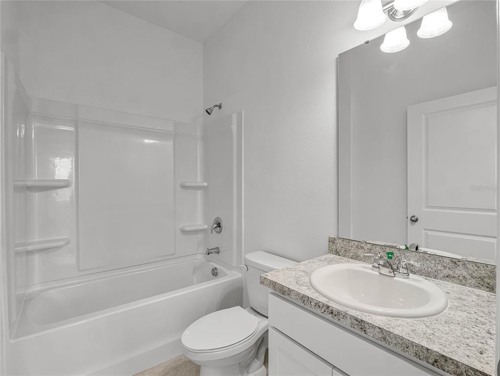 2202 Raven Rdg Road Clermont, FL 34715 - Photo 23 of 37 a bathroom with a granite countertop sink a toilet and shower