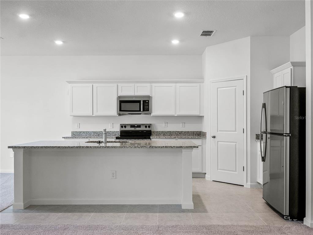2202 Raven Rdg Road Clermont, FL 34715 - Photo 7 of 37 a kitchen with stainless steel appliances a sink stove refrigerator and white cabinets with wooden floor