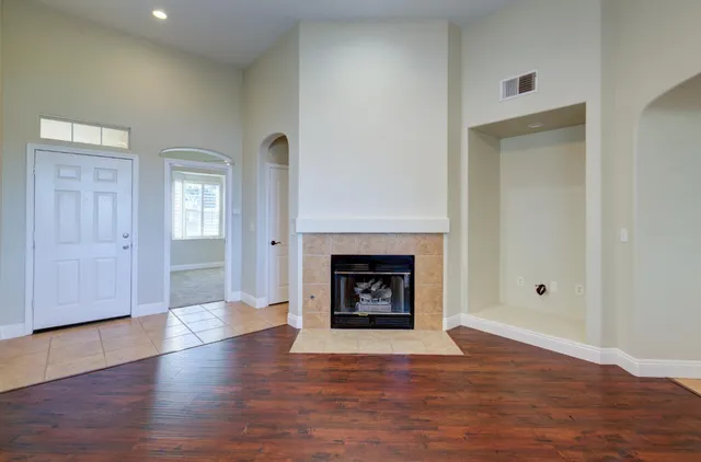 an empty room with wooden floor fireplace and windows
