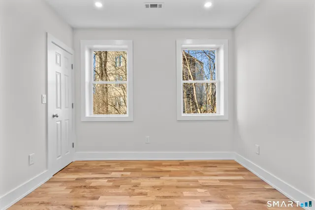 a view of empty room with window and wooden floor