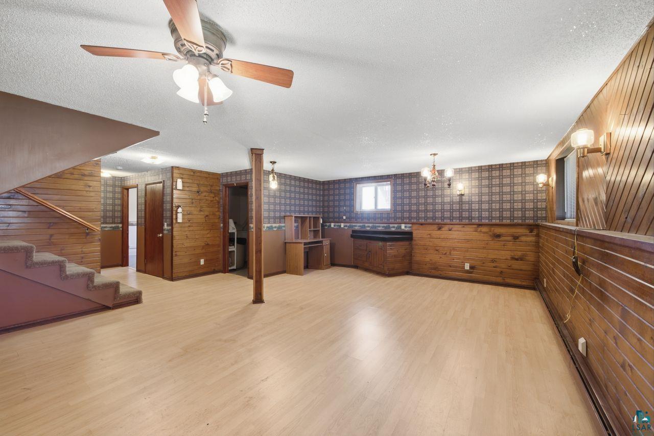 61018 Dahlstrom Road Ashland, WI 54806 - Photo 18 of 28 Lower-level room featuring light wood-finish flooring, wood paneling, and a ceiling fan