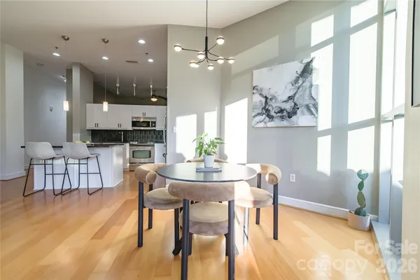 a dining room with wooden floor a chandelier a glass table and chairs